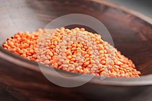 Rustic wooden bowl with raw organic red lentil grains. High protein cereal product