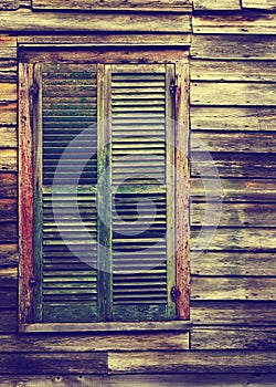 Rustic wooden building window with closed green shutters