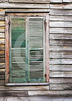 Rustic wooden building window with closed green shutters