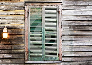 Rustic wooden building window with closed green shutters and light