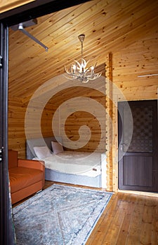Rustic wooden cabin interior with bed, sofa, and armoire