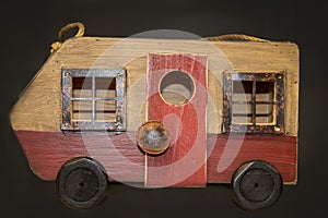 Rustic wooden camper van pull toy with rusty windows against dark brown background