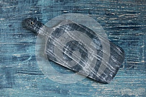 Rustic wooden cutting board on blue textured table background