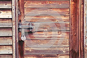 Rustic wooden door closed with padlock.