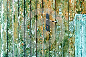 Rustic wooden door and handle with paint peeling off the surface