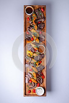 Rustic wooden platter with assorted meats and vegetables
