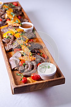 Rustic wooden platter with assorted meats and vegetables