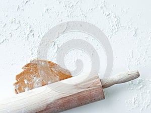 Rustic wooden rolling pin with cookie dough on floured surface photo