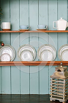 Rustic wooden shelves with ceramic utensils, plates and tea set