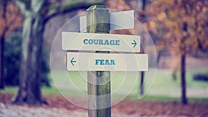 Rustic wooden sign in an autumn park with the words Courage - Fe