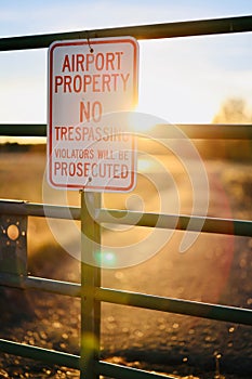 Rustic wooden signpost in a natural landscape at sunset - Airport property, No trespassing