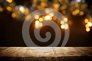 rustic wooden table in front of glitter black and gold bokeh lights.