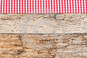 Rustic wooden table surface with red checkered cloth, top view