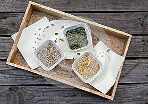 Rustic wooden tray with bowls filled with pumpkin seeds, buckwheat and sunflower seeds