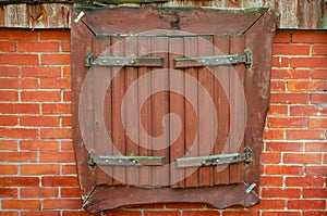 Rustic wooden window with closed shutters on redbricks wall