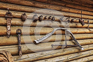 Rustic wrought iron utensils on the wall of a wooden log house. House in the village