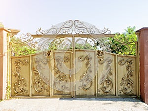 Rusting gate with forged pattern. Iron gate with wrought iron pattern. Beige iron gate with wrought iron pattern and