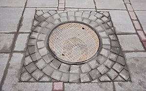 Rustproof manhole cover on the background of paving tiles, urban networks
