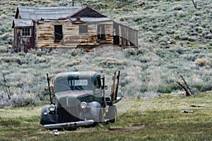 A rusty abandoned jalopy truck sits in a field in the ghost town