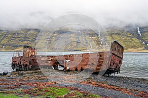 Rusty and abandoned old ship wreck from world war two laying on land in Mjoifjordur in Iceland.