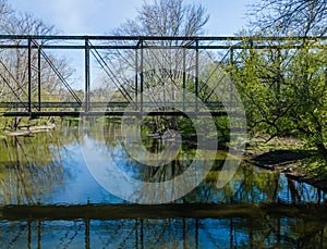 A rusty abandoned steel truss bridge over a small slow moving river. photo