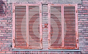 Rusty aged metallic shutter on building brick wall