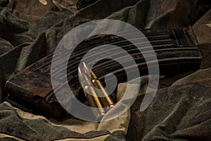 Rusty AK-47 magazine and bullets on camouflage textile background