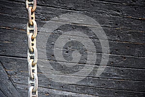 Rusty anchor chain on the background of an old wooden decorative ship