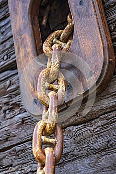 rusty anchor chain coming out of a wooden sailing ship.