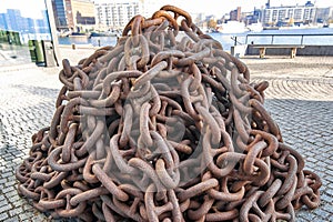 Rusty anchor chain piled up on the pier, close-up