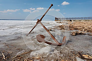 Rusty anchor on the frozen lake coast