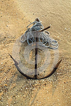 RUSTY ANCHOR WET BEACH SAND AND WHITE SEA WAVE FOAM