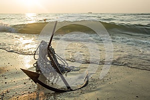 RUSTY ANCHOR WET BEACH SAND AND WHITE SEA WAVE FOAM