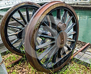 Rusty antique wheel next to river.