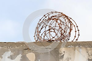 rusty barbed wire coil on top of a concrete wall