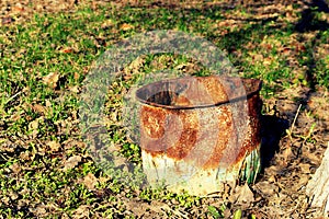 Rusty barrel in the garden on dry and green grass