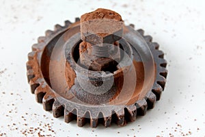 Rusty bolt, nut and gear wheel made of chocolate isolated on white background