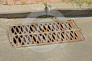 brown iron drain grate on gray asphalt road
