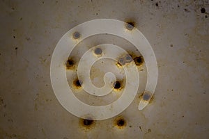 Rusty bullet holes in a metal plate.