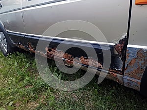 Rusty car doors and thresholds with a hole
