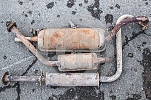 Rusty car exhaust system on the pavement