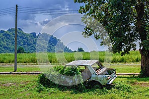 Rusty car wreck, Derelict old car is overgrown with grass, An old rusted out scrap car that has been abandoned mountains under th