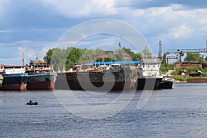 Rusty cargo ships and lonely fisherman on boat on summer