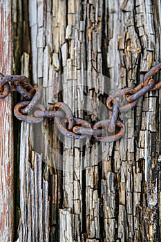 A rusty chain on the background of an aged wooden board.