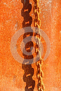 Rusty chain on the background of a rusty steel plate casts a shadow, background in rusty tones