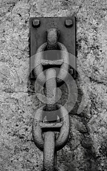 RUSTY CHAIN BOLTED TO ROCK
