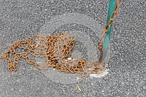 Rusty chain from a fence in a parking lot, the view of which is inappropriate in the city center.