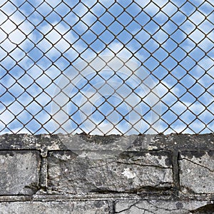 Rusty chain link fence, white grey brick wall texture background, blue summer sky and clouds, vertical  old aged weathered