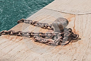Rusty chain on mooring or towing bollard at harbor