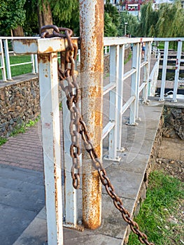 rusty chain is tied to a metal railing. Boat mooring. Reliable old chain